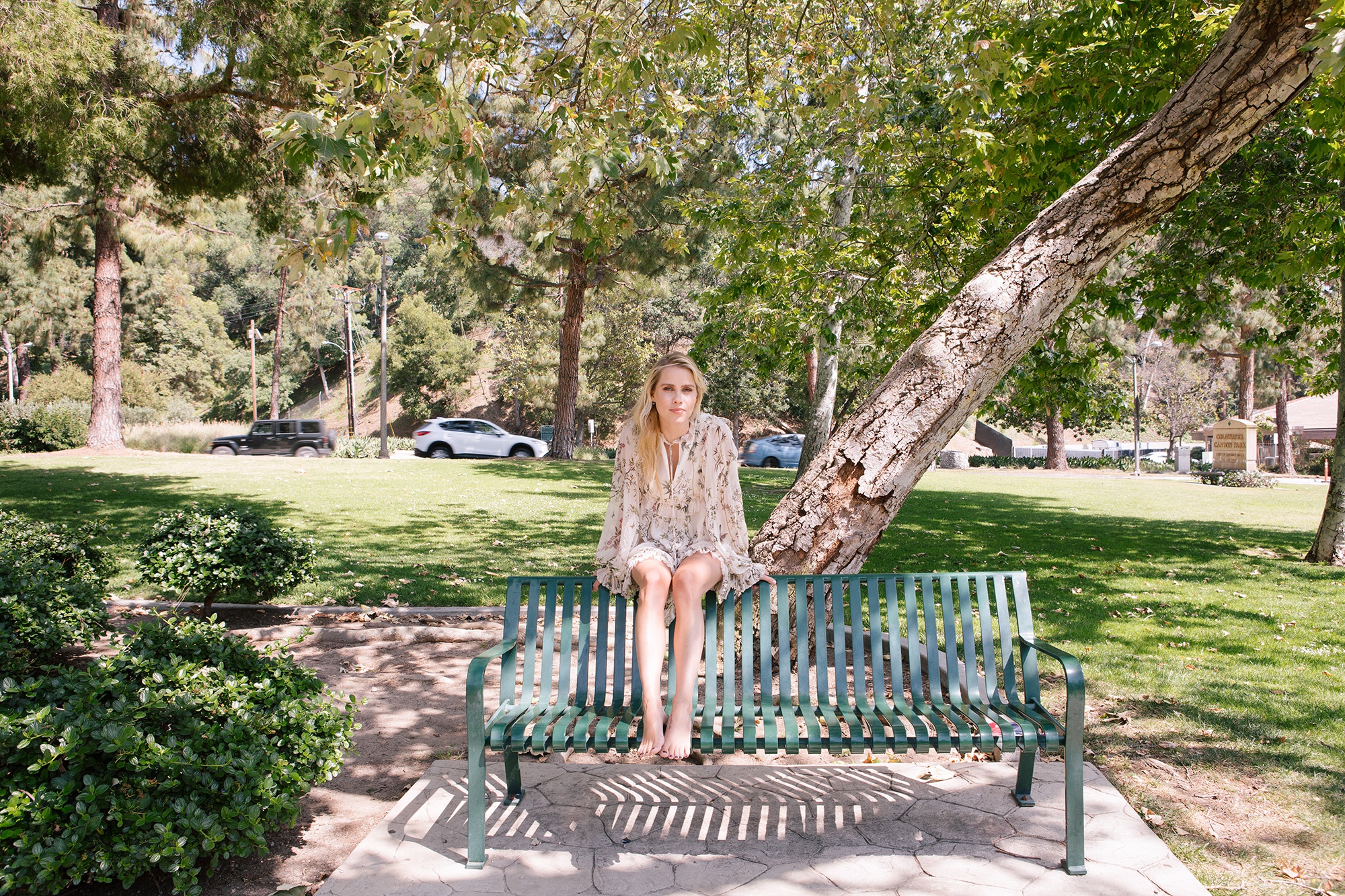 Блондинка раздвигает ноги на скамейке в парке